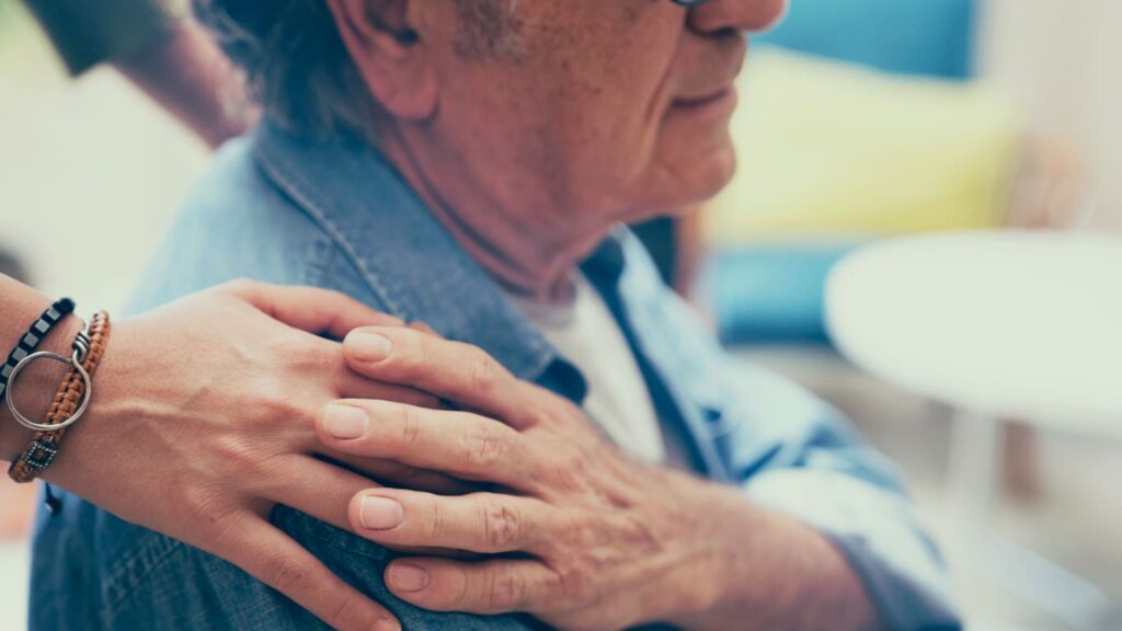 hand on shoulder of elderly man